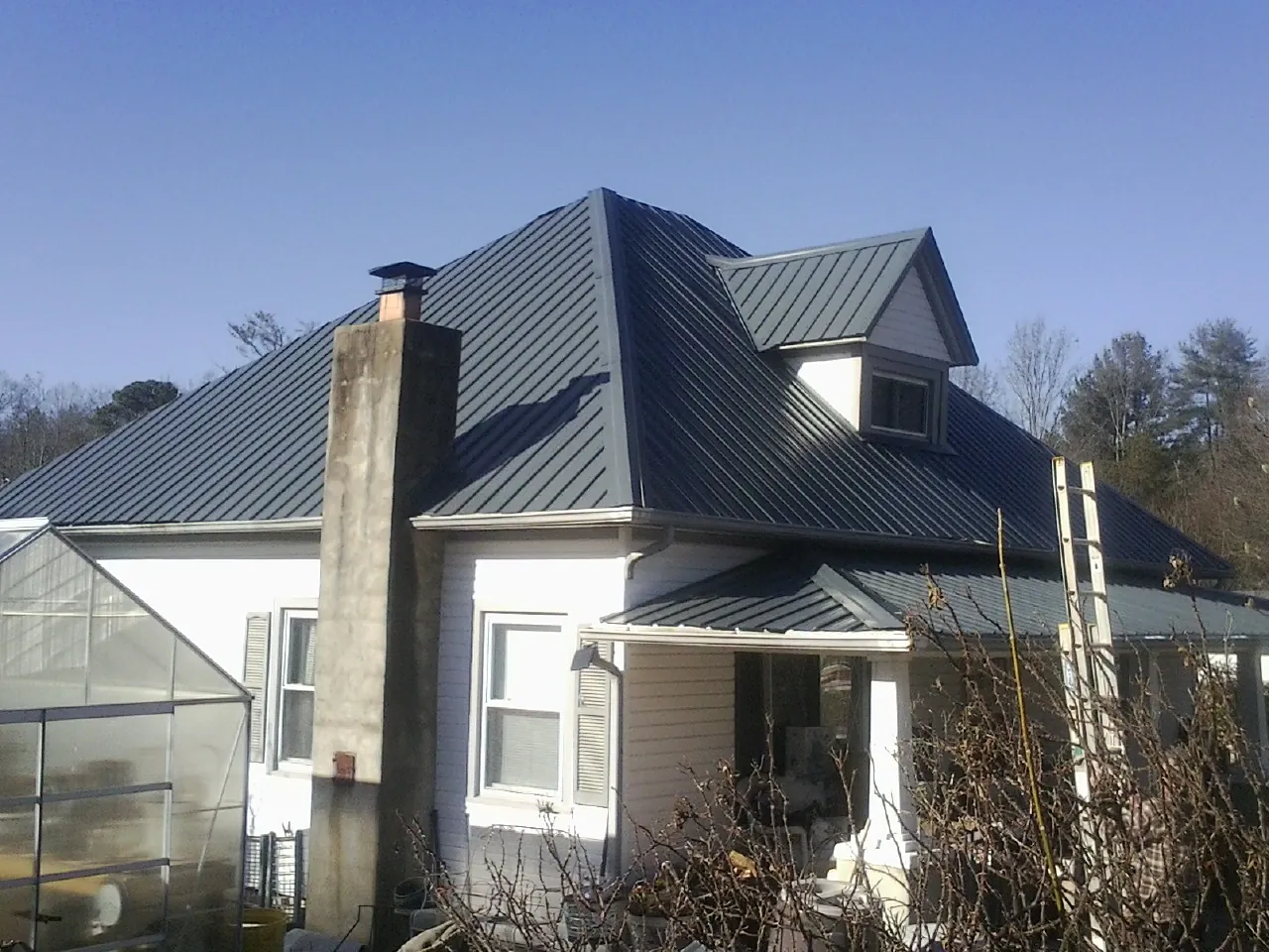 Dark blue standing seam metal roof on a white farmhouse with dormer — Slate & Tile Roof Repair by Roofing Brothers in Wood River Junction