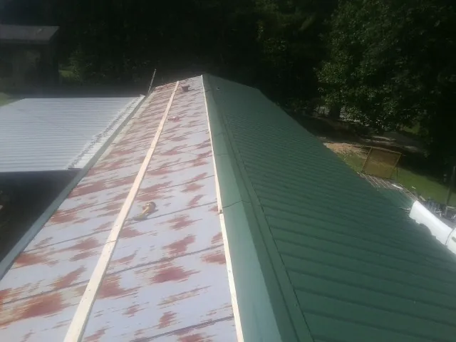 Old rusted panels beside newly installed green metal roofing — Wind Damage Roof Repair by Roofing Brothers in Wood River Junction