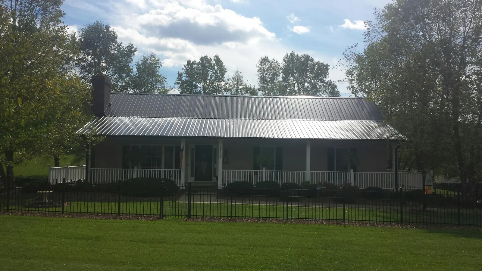 Gray metal roof on a brick ranch with a full width front porch — Gutter Guard Installation work by our crew in Wood River Junction