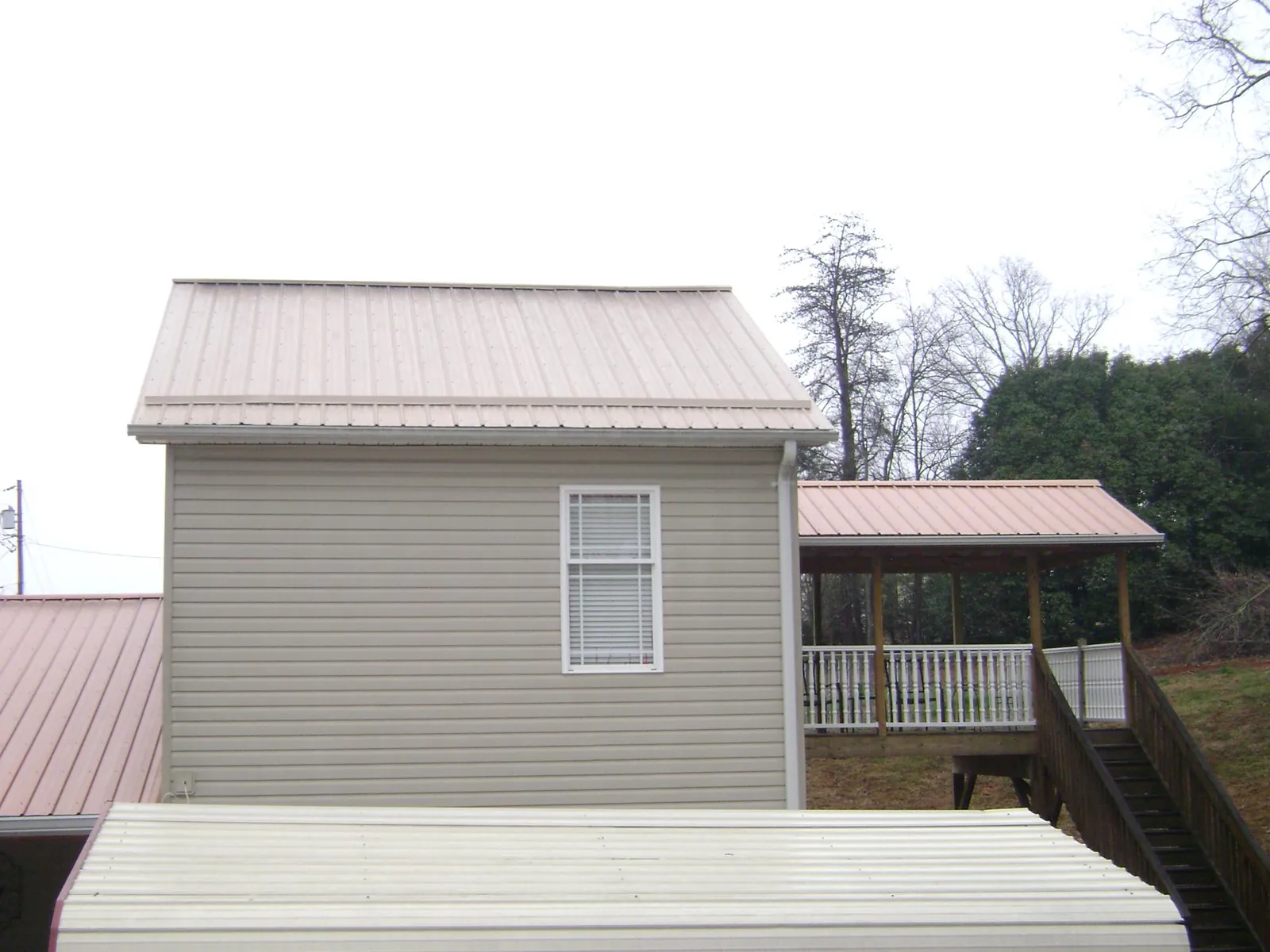 Tan metal roofs on a two story addition and attached porch, from a Roof Replacement job in Wood River Junction