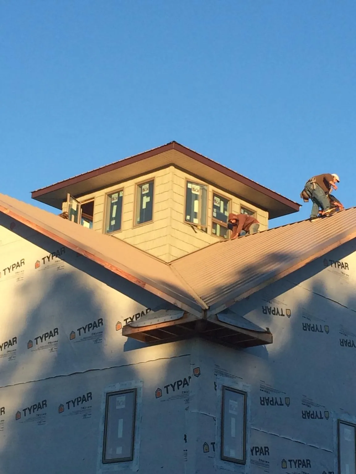 Roofers working around a rooftop cupola on a new metal roof at sunset — Roof Waterproofing in Wood River Junction by Roofing Brothers